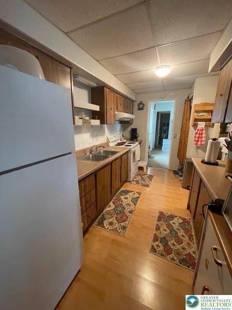 10 Springridge Rd, Moore Twp, PA 18014 - kitchen with white appliances, under cabinet range hood, brown cabinets, a sink, and light wood-style flooring