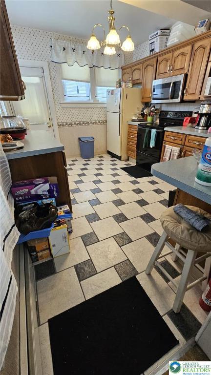 511 N 8th St, Allentown City, PA 18102 - kitchen featuring stainless steel microwave, electric range, wallpapered walls, freestanding refrigerator, and a chandelier
