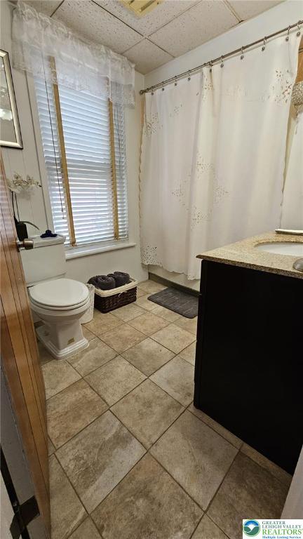 511 N 8th St, Allentown City, PA 18102 - full bath featuring toilet, vanity, tile patterned flooring, a paneled ceiling, and a shower with curtain