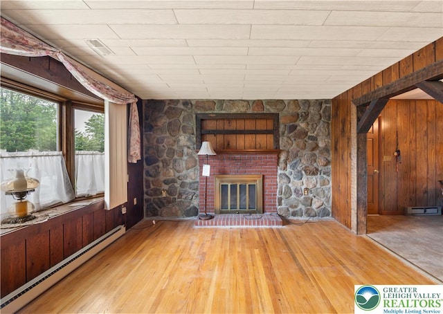 155 7th St, Tatamy Borough, PA 18085 - unfurnished living room featuring a baseboard radiator, hardwood / wood-style floors, wood walls, and a glass covered fireplace