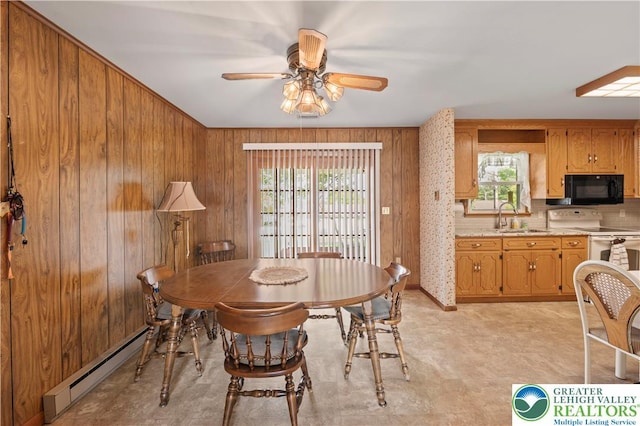 155 7th St, Tatamy Borough, PA 18085 - dining room with baseboard heating, a ceiling fan, light flooring, and wood walls