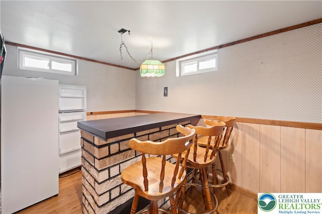 155 7th St, Tatamy Borough, PA 18085 - dining room with light wood-type flooring, a bar, wallpapered walls, ornamental molding, and a wainscoted wall