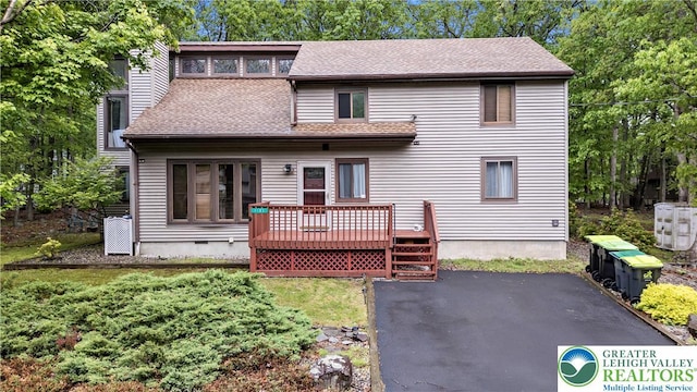 1117 Belaire Dr, Stroud Twp, PA 18301 - rear view of house with a wooden deck, roof with shingles, a patio area, and view of scattered trees