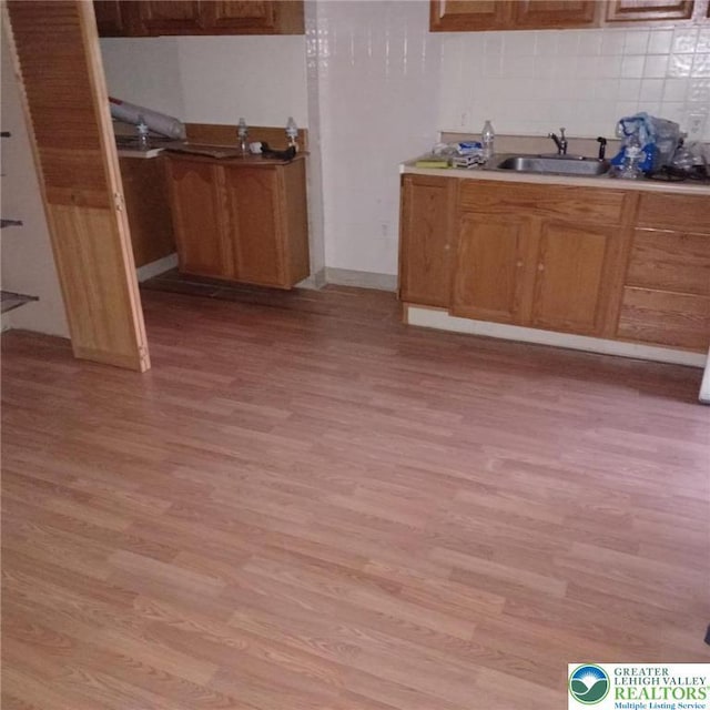 617 Oak St, Allentown City, PA 18102 - kitchen with light wood finished floors, a sink, backsplash, light countertops, and brown cabinetry
