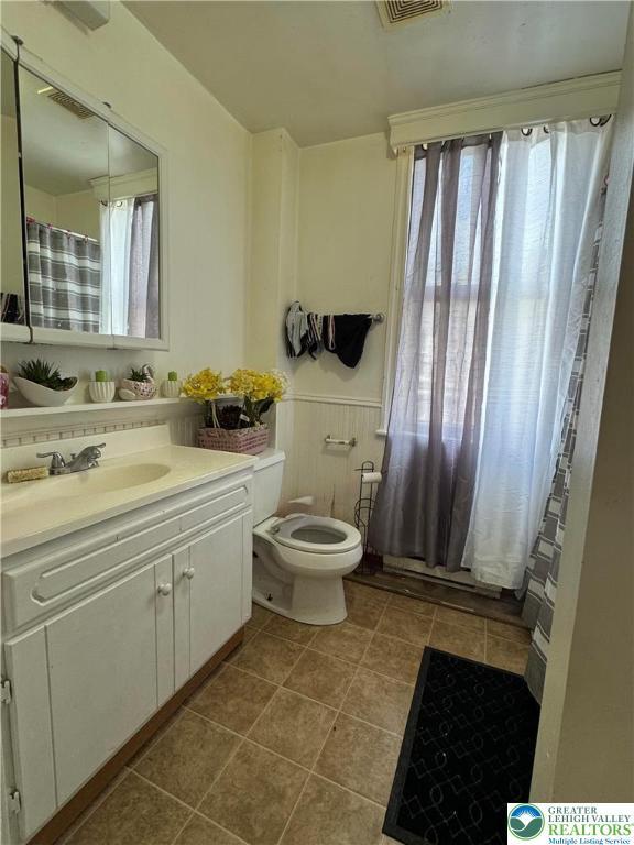 528 N 6th St, Allentown City, PA 18102 - full bath featuring toilet, vanity, tile patterned floors, and wainscoting