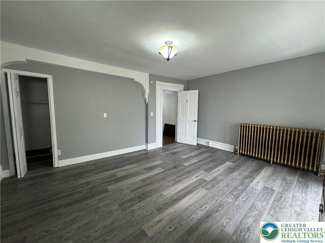 528 N 6th St, Allentown City, PA 18102 - unfurnished bedroom featuring radiator heating unit, arched walkways, dark wood-style flooring, baseboards, and a closet