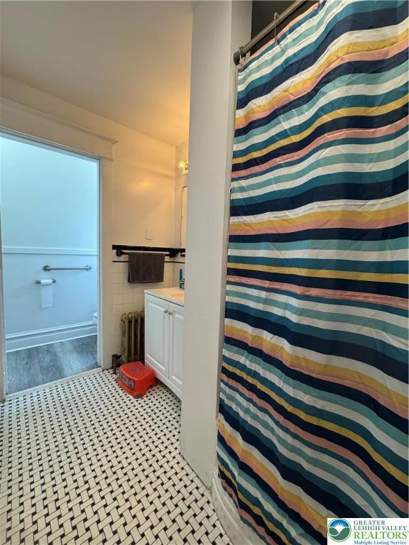 528 N 6th St, Allentown City, PA 18102 - full bathroom featuring radiator, vanity, toilet, wood finished floors, and tile walls