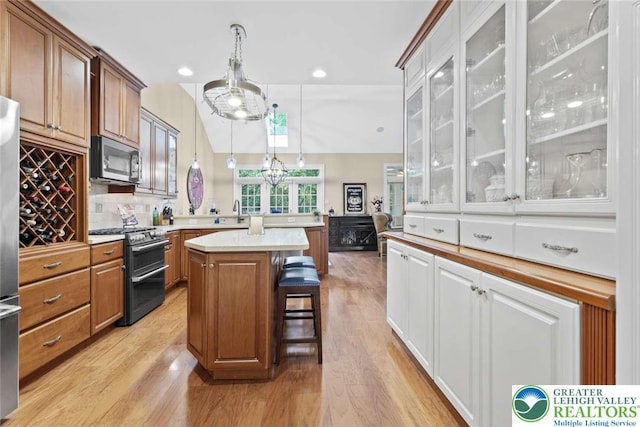 4741 Pinehurst Cir, Upper Saucon Twp, PA 18034 - kitchen with stainless steel appliances, a peninsula, glass insert cabinets, light wood finished floors, and a kitchen bar