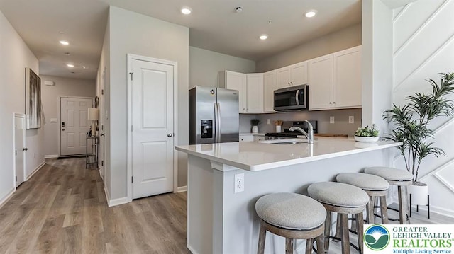 1225 Susan Cir, Upper Macungie Twp, PA 18031 - kitchen with stainless steel appliances, a breakfast bar, a peninsula, light wood-style flooring, and white cabinetry