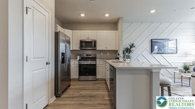1225 Susan Cir, Upper Macungie Twp, PA 18031 - kitchen featuring appliances with stainless steel finishes, a peninsula, light wood finished floors, a breakfast bar, and light countertops