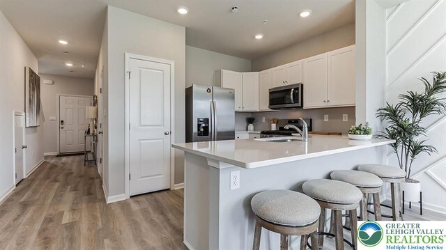 1155 Martin Rd, Upper Macungie Twp, PA 18031 - kitchen with stainless steel appliances, a breakfast bar, a peninsula, light wood-style flooring, and white cabinetry