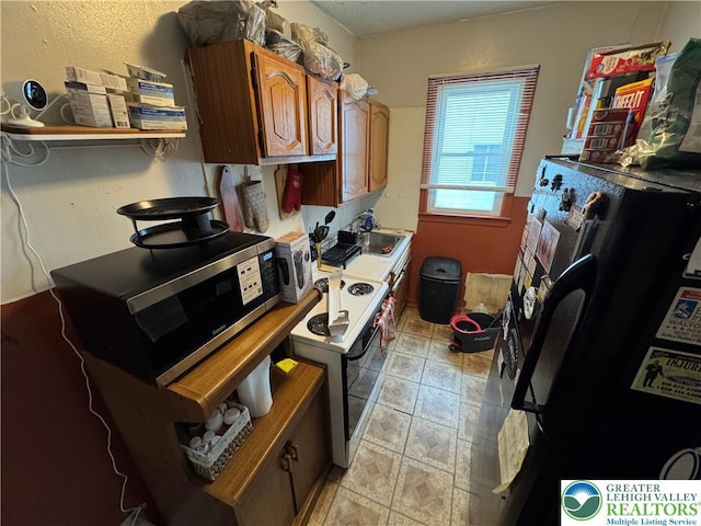 321 W Broad St, Tamaqua Borough, PA 18252 - kitchen with stainless steel microwave, electric range, freestanding refrigerator, a sink, and brown cabinetry