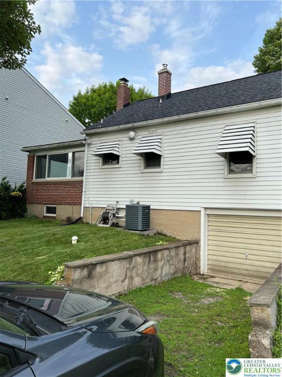 1540 Riegel St, Hellertown Borough, PA 18055 - back of house featuring central AC, a lawn, a garage, a chimney, and a shingled roof