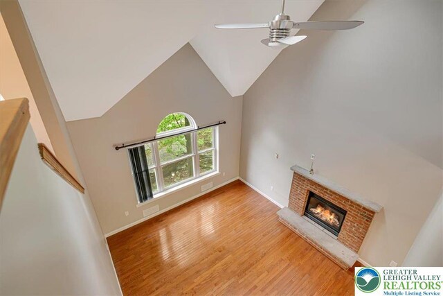 2330 Burntwood Dr, East Stroudsburg, PA 18301 - unfurnished living room featuring a brick fireplace, ceiling fan, light wood-style floors, and high vaulted ceiling