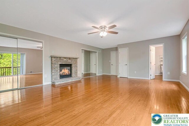 2330 Burntwood Dr, East Stroudsburg, PA 18301 - unfurnished living room with ceiling fan, light wood-style flooring, and a glass covered fireplace