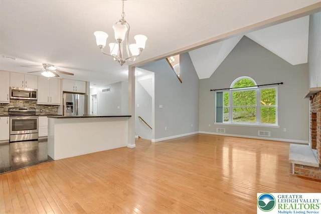 2330 Burntwood Dr, East Stroudsburg, PA 18301 - unfurnished living room featuring light wood-type flooring, a chandelier, a ceiling fan, a fireplace, and lofted ceiling