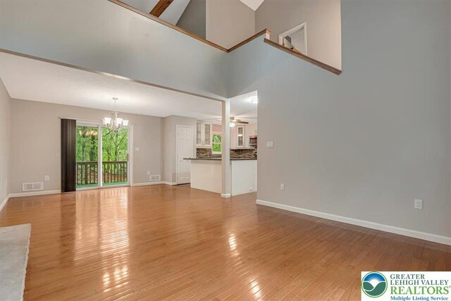 2330 Burntwood Dr, East Stroudsburg, PA 18301 - unfurnished living room with a chandelier, light wood-type flooring, a towering ceiling, and a ceiling fan