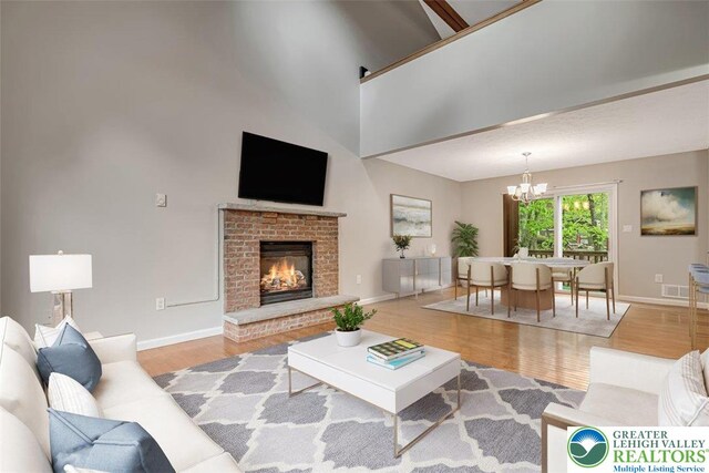 2330 Burntwood Dr, East Stroudsburg, PA 18301 - living room featuring a chandelier, wood finished floors, a high ceiling, and a brick fireplace