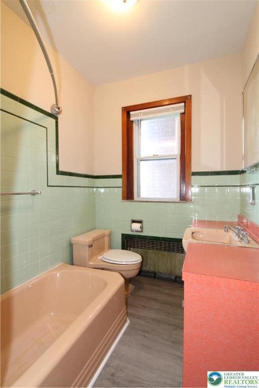1171 E 4th St, Bethlehem City, PA 18015 - bathroom with radiator, tile walls, toilet, a bath, and wood finished floors