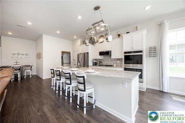 7911 Schaefer Crst, Upper Macungie Twp, PA 18031 - kitchen with appliances with stainless steel finishes, a sink, a center island with sink, tasteful backsplash, and dark wood-style floors