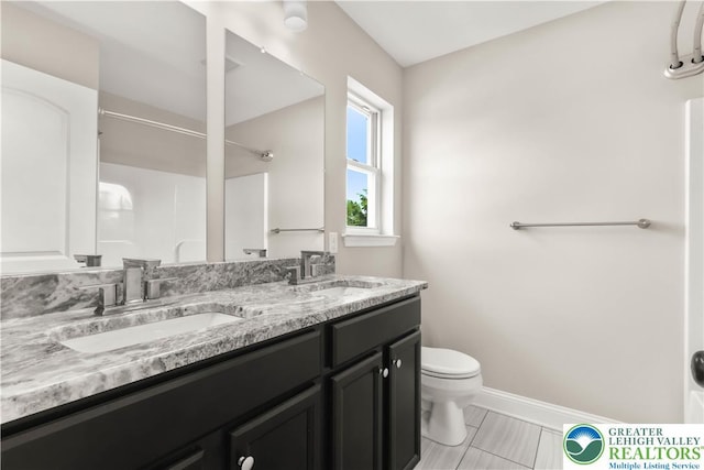 721 7th St, Whitehall Twp, PA 18052 - bathroom featuring toilet, double vanity, baseboards, and a shower