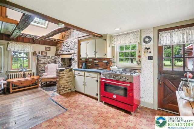 1132 Upperstump Rd, Hilltown Twp, PA 18914 - kitchen featuring range with gas stovetop, a skylight, dark countertops, a fireplace, and brick patterned floors