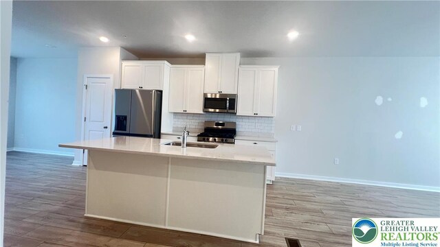 4904 Brookside Ct, Upper Saucon Twp, PA 18036 - kitchen featuring stainless steel appliances, a sink, light wood-type flooring, decorative backsplash, and a center island with sink