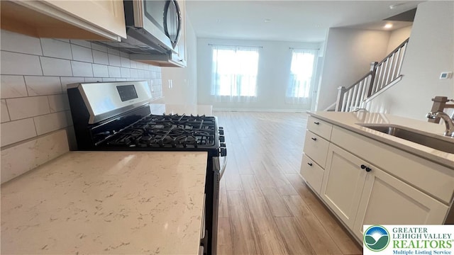 4904 Brookside Ct, Upper Saucon Twp, PA 18036 - kitchen featuring stainless steel appliances, light wood finished floors, a sink, white cabinets, and light stone countertops