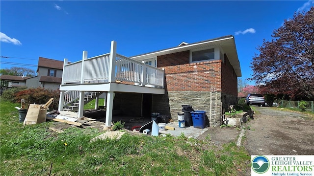1126 Charles St, Luzerne, PA 18702 - rear view of property featuring a wooden deck, stairway, brick siding, stone siding, and dirt driveway