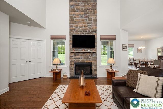 222 Danbury Dr, Bushkill Twp, PA 18064 - living area featuring a stone fireplace, wood finished floors, a high ceiling, a chandelier, and baseboards