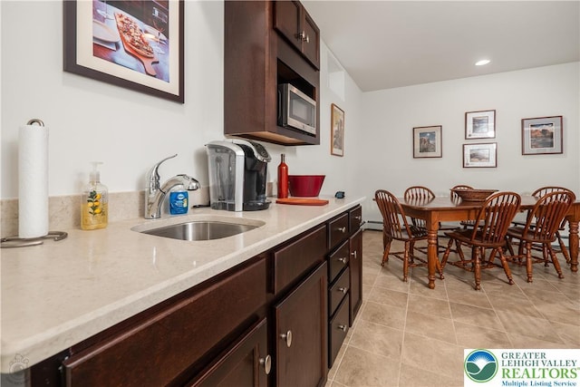 222 Danbury Dr, Bushkill Twp, PA 18064 - kitchen featuring a sink, stainless steel microwave, dark brown cabinetry, light tile patterned flooring, and light stone counters