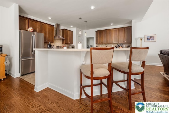 222 Danbury Dr, Bushkill Twp, PA 18064 - kitchen with stainless steel appliances, wall chimney range hood, backsplash, wood finished floors, and recessed lighting