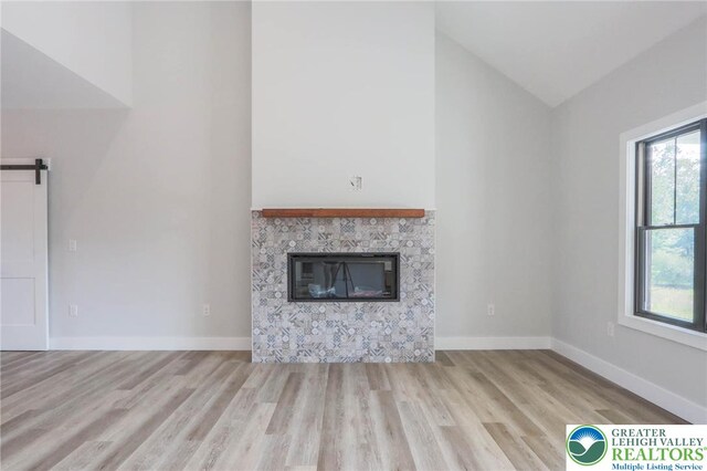 448 Long Lane Rd, Lehigh Twp, PA 18088 - unfurnished living room with wood finished floors, healthy amount of natural light, high vaulted ceiling, a barn door, and a glass covered fireplace
