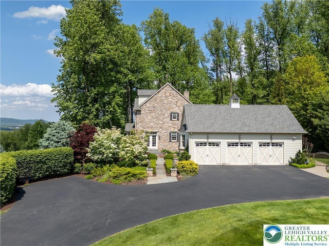 5355 Saucon Ridge Rd, Upper Saucon Twp, PA 18036 - view of front facade with stone siding, asphalt driveway, an attached garage, and a chimney
