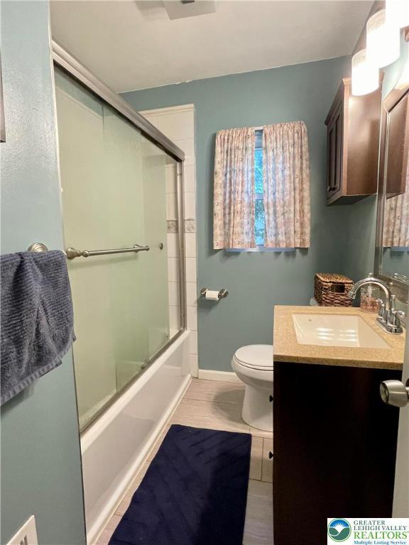 938 N Broad St, Allentown City, PA 18104 - full bathroom featuring vanity, toilet, enclosed tub / shower combo, baseboards, and tile patterned flooring