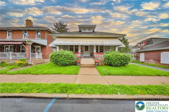 30 S 16th St, Wilson Boro, PA 18042 - view of front of property featuring covered porch, brick siding, a chimney, and a front lawn