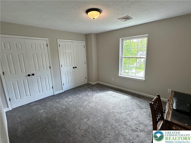 7190 Rimrock Dr, Coolbaugh Twp, PA 18466 - unfurnished bedroom featuring multiple closets, dark carpet, baseboards, and a textured ceiling