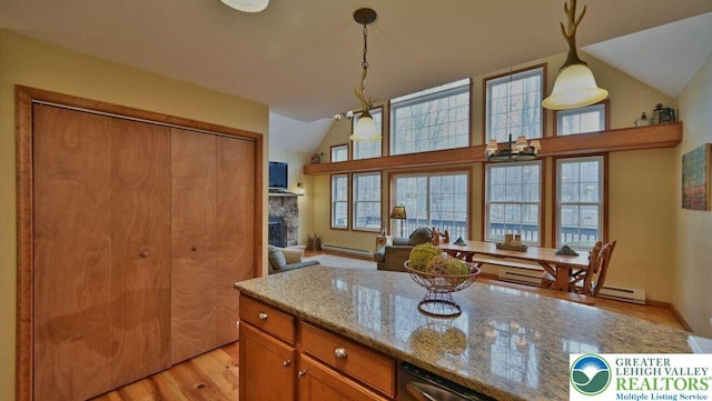 97 Lucretius Trl, Penn Forest Twp, PA 18210 - kitchen featuring baseboard heating, light wood-style flooring, lofted ceiling, brown cabinetry, and light stone countertops
