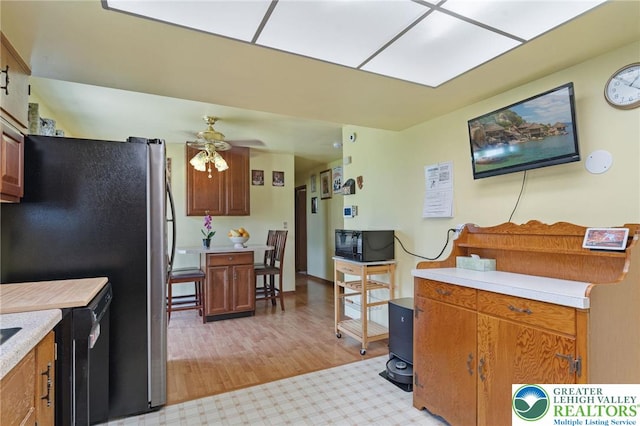94 Brader Dr, Luzerne, PA 18705 - kitchen with black microwave, light countertops, a ceiling fan, freestanding refrigerator, and light wood-type flooring