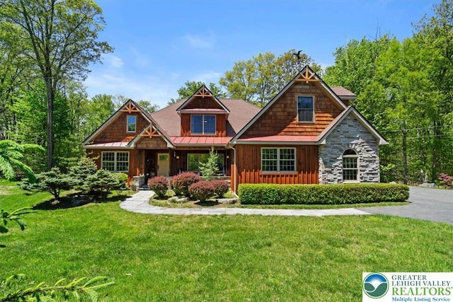 127 Timber Lake Dr, Barrett Twp, PA 18325 - craftsman-style home with board and batten siding, a front yard, a standing seam roof, stone siding, and covered porch