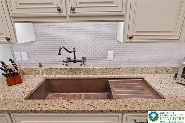 127 Timber Lake Dr, Barrett Twp, PA 18325 - kitchen featuring tasteful backsplash, light stone counters, cream cabinetry, and a sink