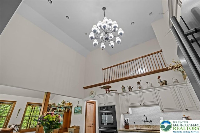 127 Timber Lake Dr, Barrett Twp, PA 18325 - kitchen with high vaulted ceiling, a sink, decorative backsplash, a chandelier, and pendant lighting