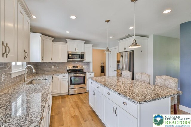 217 E Dell Rd, Moore Twp, PA 18014 - kitchen with appliances with stainless steel finishes, a sink, a center island, light wood finished floors, and decorative backsplash