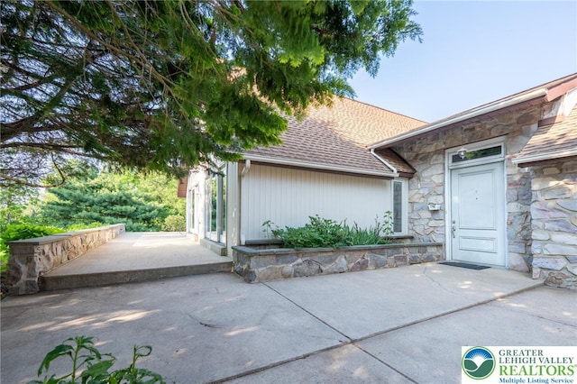 68 Knoll Cir, Boyertown, PA 19512 - doorway to property with stone siding, a shingled roof, and a patio