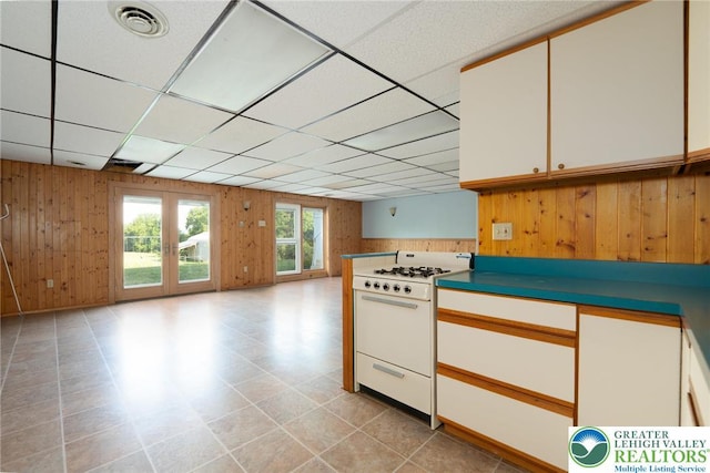 68 Knoll Cir, Boyertown, PA 19512 - kitchen with white range with gas stovetop, wood walls, a paneled ceiling, white cabinets, and open floor plan