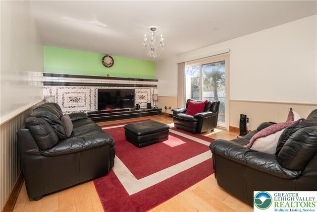 990 Hill Dr, Lower Macungie Twp, PA 18103 - living room featuring wood finished floors, wainscoting, a chandelier, and a glass covered fireplace