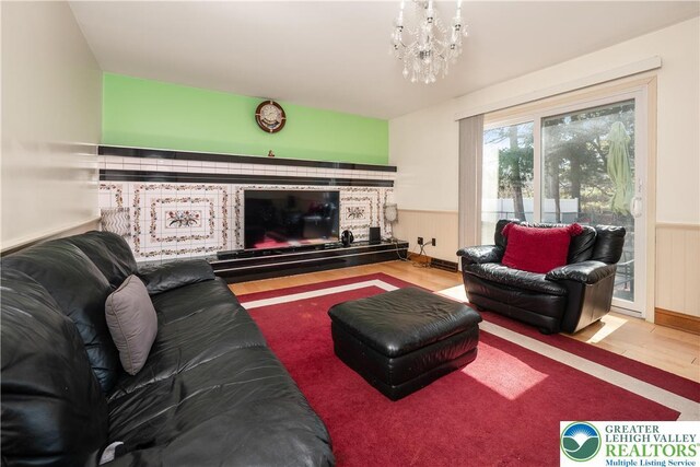 990 Hill Dr, Lower Macungie Twp, PA 18103 - living area featuring a glass covered fireplace, wainscoting, wood finished floors, and a chandelier
