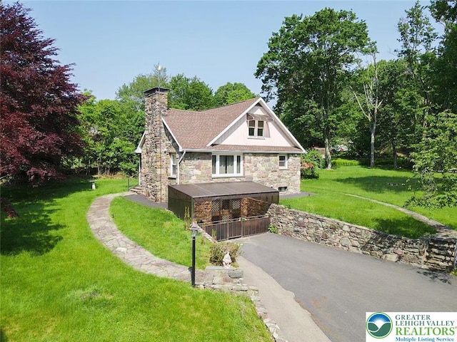116 Peechatka, Pocono Twp, PA 18332 - view of side of home with stone siding, driveway, a chimney, and a yard