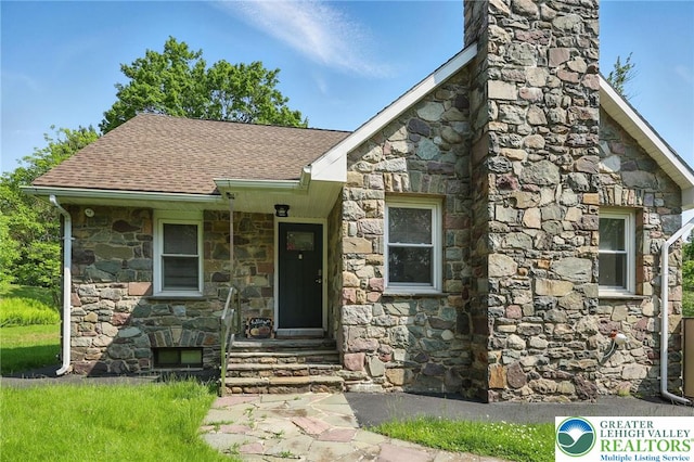 116 Peechatka, Pocono Twp, PA 18332 - view of front facade featuring stone siding, roof with shingles, and a chimney