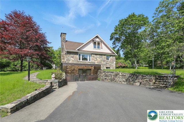 116 Peechatka, Pocono Twp, PA 18332 - view of front of home with stone siding, a chimney, driveway, and a front lawn